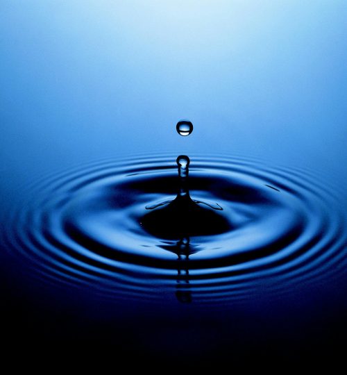 Stunning close-up of a water drop creating ripples on a serene blue surface.